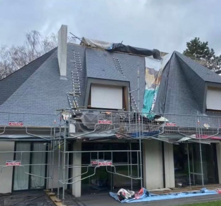 Maison sous échafaudage, toiture en ardoise en cours de reprise