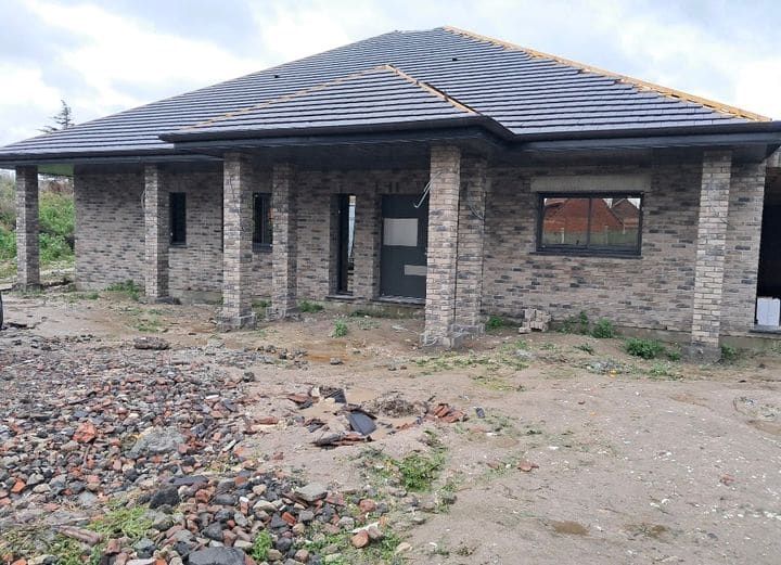 Maison terminée avec toiture à quatre pans et façade en brique