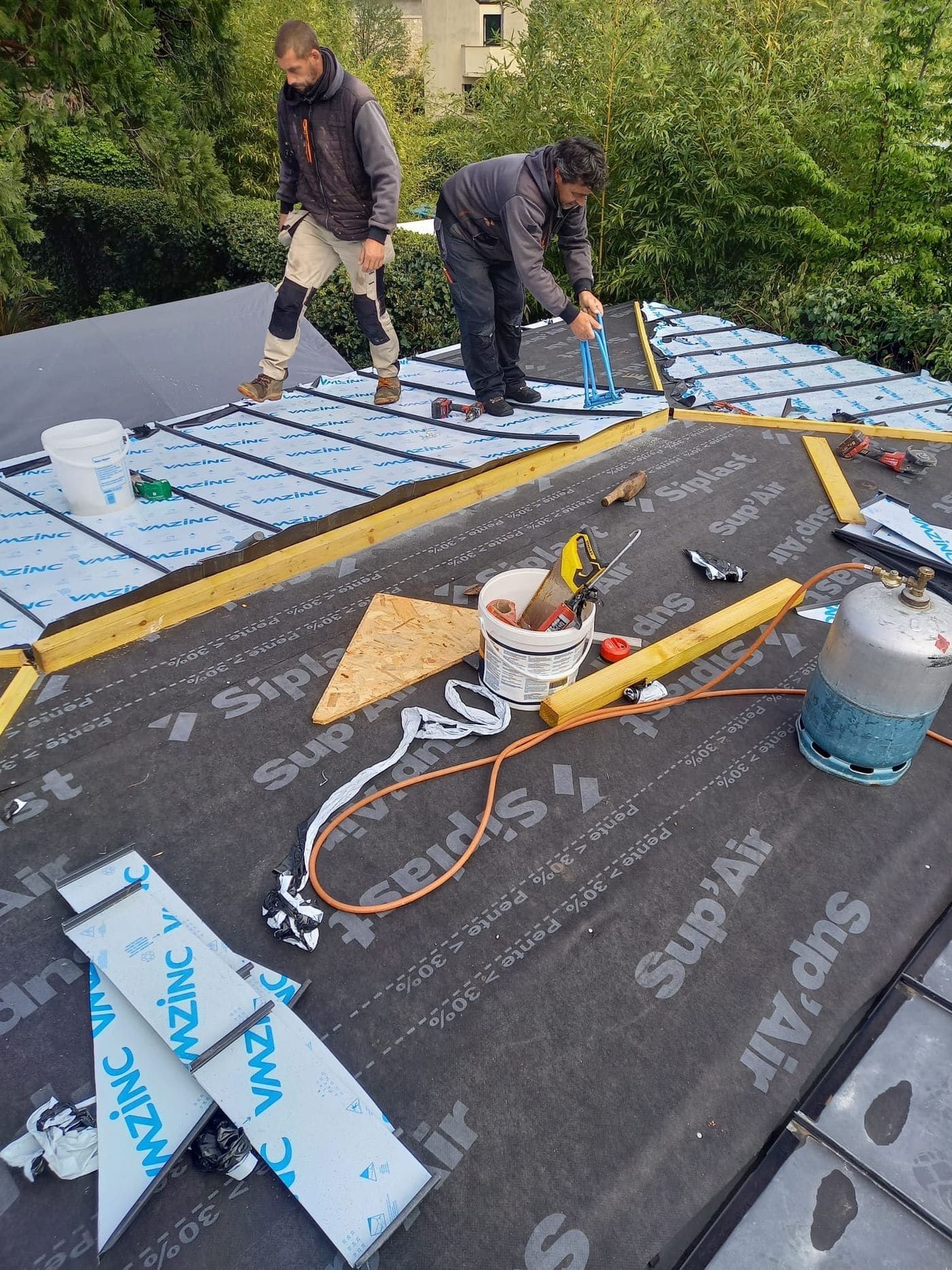 Deux couvreurs CZIR62 posant isolant et membrane sur une toiture-terrasse