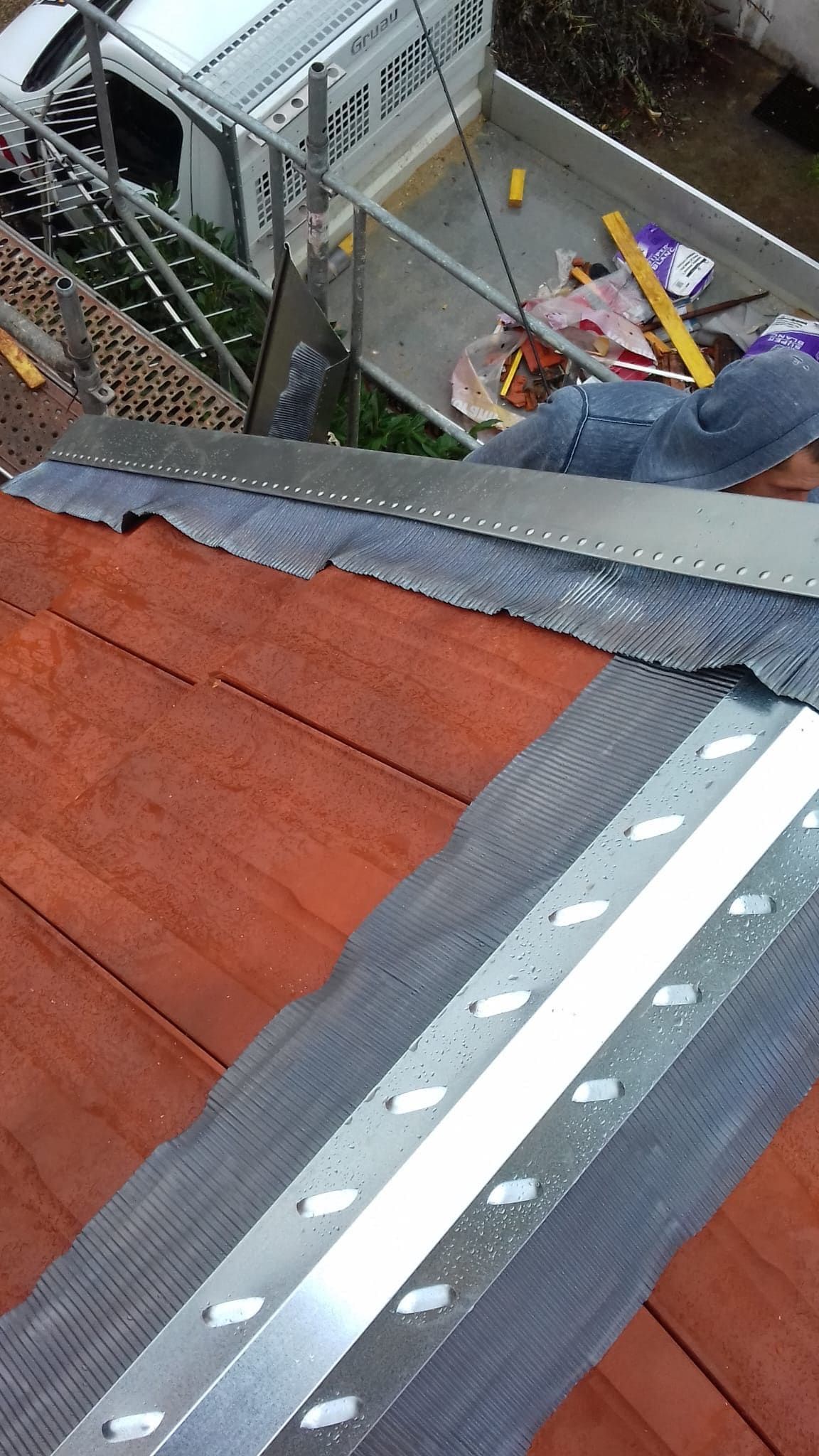 Couvreur CZIR62 manipulant une bande de zinc sur une toiture